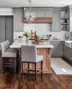 a kitchen with gray cabinets and white counter tops, wooden flooring and an island in the middle