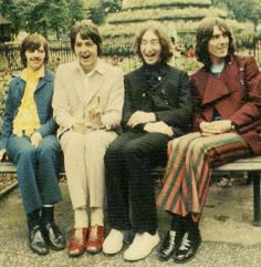 the beatles are sitting on a bench together