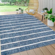 a blue and white area rug on a wooden deck with potted plants in the background