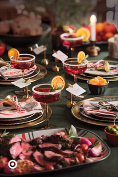 a table topped with plates and bowls filled with food covered in sauces next to candles