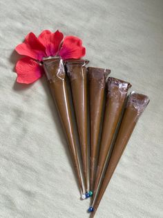 four chocolate cones with flowers on them sitting on a white tablecloth covered bed sheet