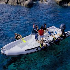 a group of people standing on the back of a white boat in clear blue water