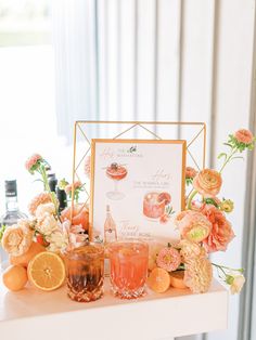 a table topped with oranges and glasses next to a sign that reads the cocktail menu