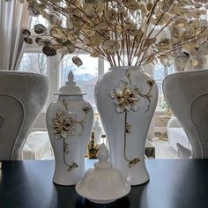 three white vases sitting on top of a table