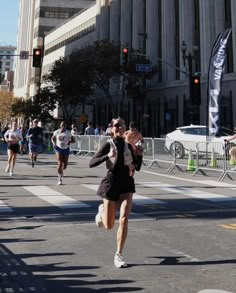 people are running in the street with buildings in the backgroung and onlookers