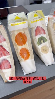 four packaged sandwiches with fruit on them sitting on a counter