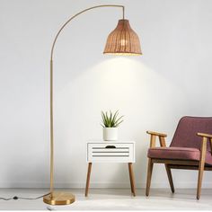 a lamp that is next to a table with a potted plant on it and a chair