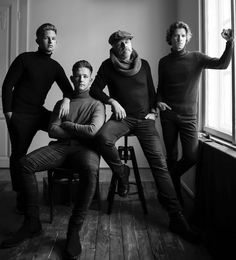 three men are posing for a black and white photo in front of a large window