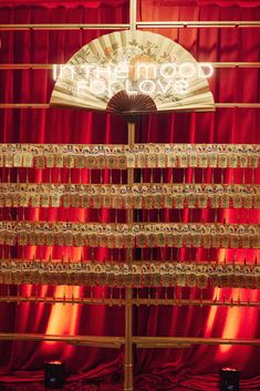 an image of a red curtain with a fan in the center and lights above it