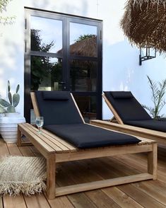 two chaise lounge chairs sitting on top of a wooden deck next to a potted plant