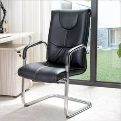 a black leather office chair sitting in front of a window