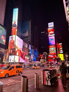 a city street filled with lots of traffic and tall buildings covered in billboards at night