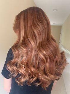 the back of a woman's head with long, wavy hair in an apartment hallway