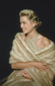 a woman wearing a fur stole with her arms crossed