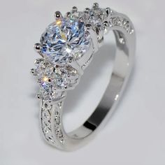 a white gold engagement ring with three stones on the side and an intricate band around it