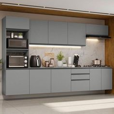 a kitchen with gray cabinets and white tile flooring is shown in this image, there are two microwaves on the counter