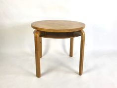 a small round wooden table with two legs on white background in front of the camera