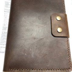 a brown leather wallet with two gold buttons