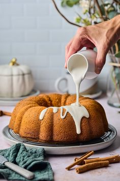 someone pouring white icing onto a bundt cake