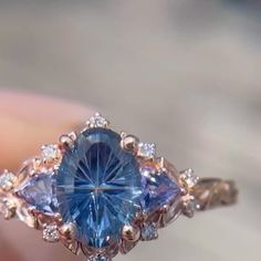 a close up of a person holding a ring with a blue stone in the middle