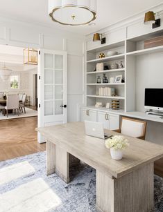 a desk with a laptop on top of it in front of a book shelf and door