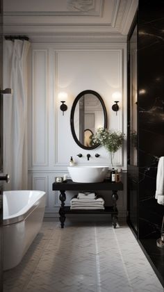 a white bath tub sitting next to a black and white sink under a round mirror