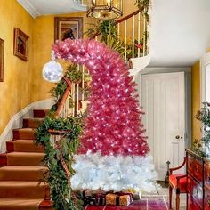 a decorated christmas tree sitting on top of a red rug next to a stair case