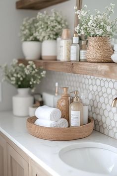 a bathroom sink with soap, lotion and flowers on the counter top in front of it