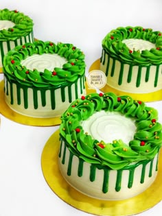 three cakes decorated with green icing and holly wreaths on gold platter plates