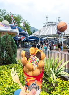 someone holding up a cup filled with doughnuts and sprinkles at an amusement park