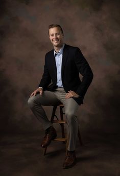 a man in a suit sitting on a stool