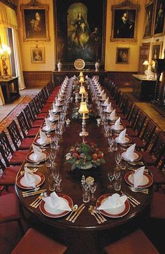 a long dining table with place settings and plates on it in an ornately decorated room