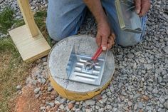 a man is working on an outdoor fire pit with tools in his hands and some rocks around him