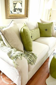 a white couch with green pillows on it