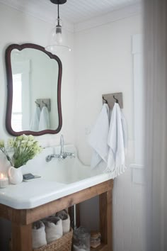 a bathroom sink sitting under a mirror next to a wooden cabinet and white towels hanging on the wall