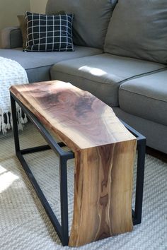 a wooden table sitting in the middle of a living room next to a gray couch