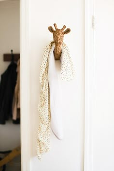 a giraffe head mounted to the side of a door with a scarf hanging on it