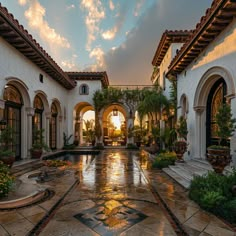 an outdoor courtyard with potted plants and water features in the foreground as the sun sets