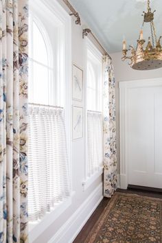 a room with curtains, rug and chandelier in it