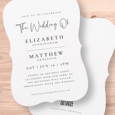 a white wedding card on top of a wooden table