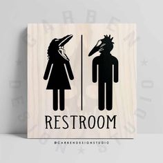 a wooden sign with the words restroom and a woman in a bird's head