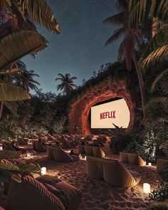 an outdoor movie theater is lit up at night with palm trees in the foreground