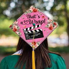 a woman wearing a pink graduation cap that says, that's a wrap