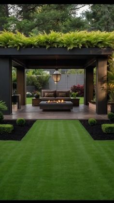 an outdoor living area with grass, couch and fire pit in the middle of it