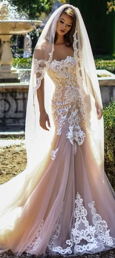 a woman in a wedding dress with a veil on her head standing next to a fountain