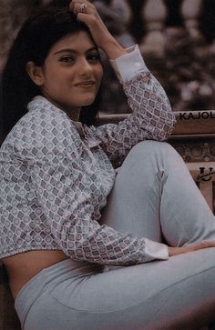 a woman sitting on top of a wooden bench next to a tree trunk with her hand on her head