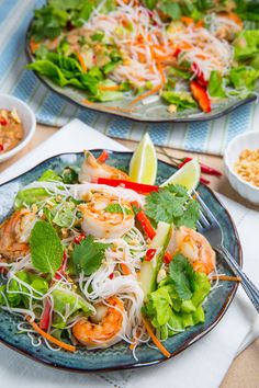 two plates filled with shrimp and veggies on top of a table