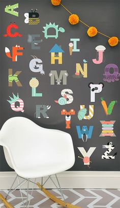 a white rocking chair sitting in front of a wall with letters painted on it's side