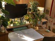 a desk with a computer monitor, keyboard and plants