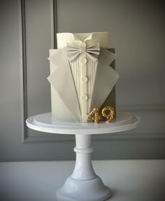 a white cake with a bow tie and gold wedding rings sitting on top of it